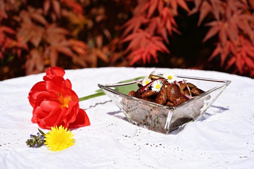 Steirischer Käferbohnensalat in einer kleinen Salatschüssel auf einem mit Blumen dekorierten Tisch